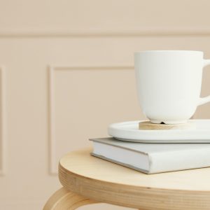 pexels-photo-6801212-6801212 A white ceramic mug on a tray, placed over a closed book on a wooden table.